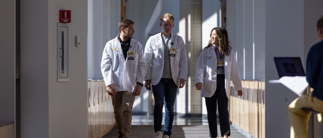 Students walking through hallway on campus in white coats