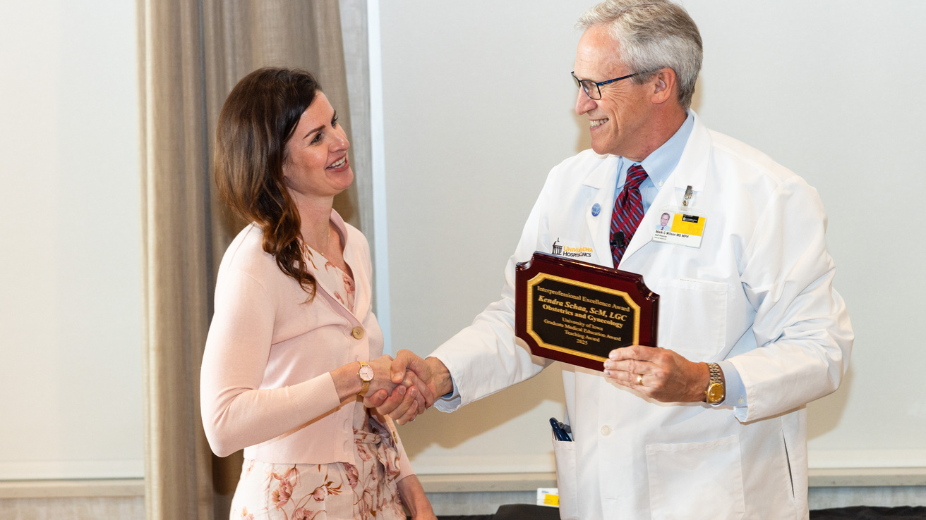 2025 Excellence in Interprofessional Education Winner, Kendra Schaa, ScM, Licensed Genetic Counselor – Obstetrics and Gynecology, receives her award from Dr. Mark Wilson.
